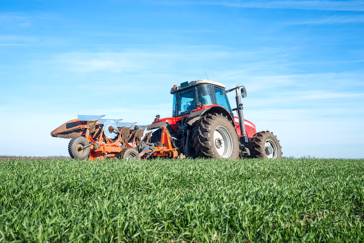 Tractor ploughing a green field at sunrise